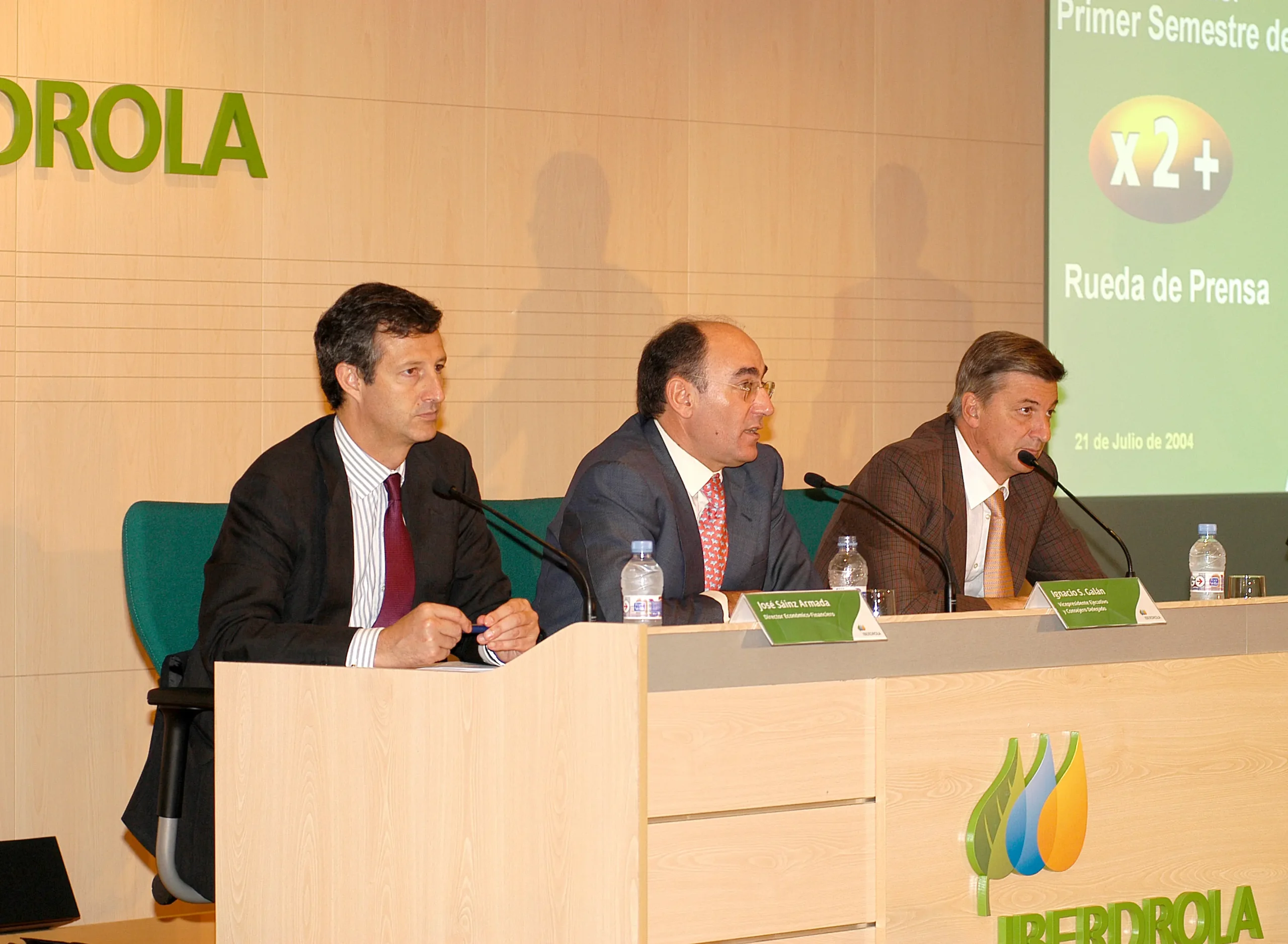 Fotografía del evento en el que Iberdrola aprueba su Plan Estratégico de 2001-2006, con el lema “x2+”, en la imagen se puede ver a 3 hombres con traje, entre ellos está Ignacio S. Galán